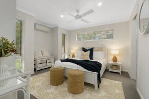 - une chambre blanche avec un lit et une chaise dans l'établissement Oscar's at Broulee Beach Luxury Coastal Living, à Broulee