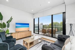 a living room with two couches and a flat screen tv at Sparkling New Apartment - Wollongong in Wollongong