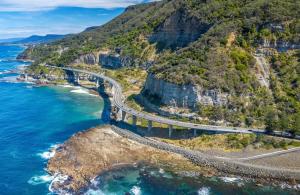 an aerial view of a road on a mountain next to the ocean at Sparkling New Apartment - Wollongong in Wollongong