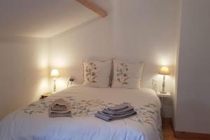 um quarto com uma cama branca e toalhas em les maisons de Jean et Eva em Nalliers