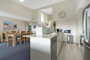 a kitchen and dining room with a clock on the wall at Spacious Townhouse in the Heart of Batemans Bay in Batemans Bay
