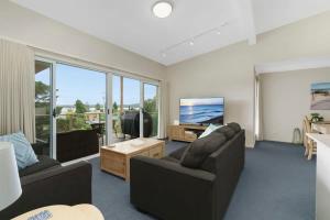a living room with two couches and a flat screen tv at Spacious Townhouse in the Heart of Batemans Bay in Batemans Bay