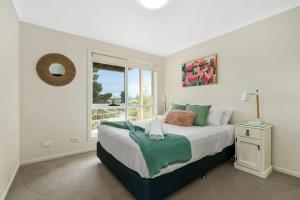 a bedroom with a large bed with a window at Spacious Townhouse in the Heart of Batemans Bay in Batemans Bay