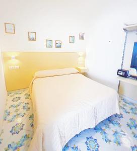 a bedroom with a white bed with a yellow headboard at B&B La Danza del Mare in Anacapri