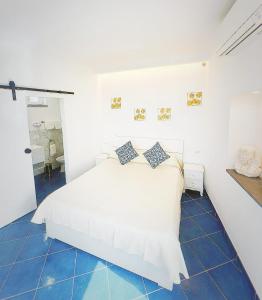 a bedroom with a white bed and blue tile floors at B&B La Danza del Mare in Anacapri