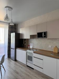 a kitchen with white cabinets and a refrigerator at 2-комнатная квартира посуточно, почасово in Kostanay