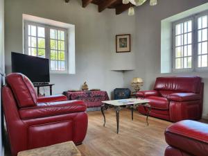 ein Wohnzimmer mit roten Ledermöbeln und einem Flachbild-TV in der Unterkunft les maisons de Jean et Eva in Nalliers