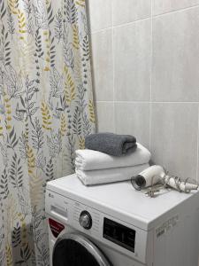 a washing machine in a bathroom with a shower curtain at 2-комнатная квартира посуточно, почасово in Kostanay