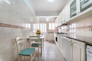 a white kitchen with a table and chairs in it at Perfect house close to beach in Armação de Pêra