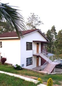 a white house with stairs and a palm tree at BEST APARTMENTS in Mbabane