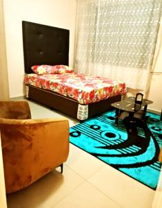 a bedroom with a bed and a chair and a carpet at BEST APARTMENTS in Mbabane