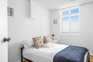 a white bedroom with a bed and a window at Spectacular Ocean View Apartment North Wollongong in Wollongong