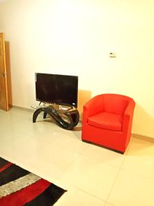 a living room with a red chair and a television at BEST APARTMENTS in Mbabane