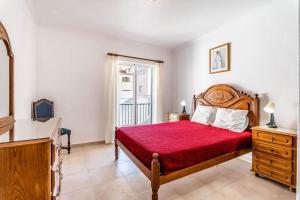 a bedroom with a bed with a red bedspread at Perfect house close to beach in Armação de Pêra