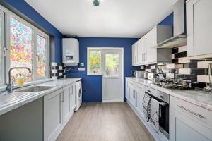 uma grande cozinha com paredes azuis e armários brancos em Spacious Luxury Garden House Free Parking em Bristol