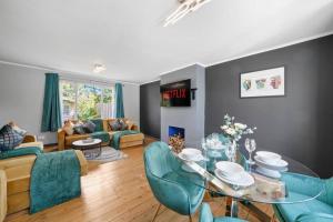 a living room with a glass table and blue chairs at Spacious Luxury Garden House Free Parking in Bristol