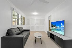 a living room with a couch and a flat screen tv at Lakeside Family Oasis - Oak Flats in Albion Park