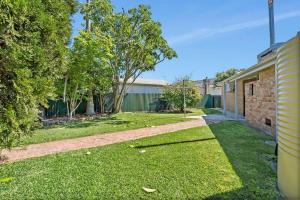 un cortile vuoto con una casa di mattoni e alberi di Lakeside Family Oasis - Oak Flats ad Albion Park