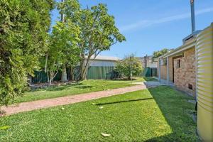 an empty yard with a brick house and trees at Lakeside Family Oasis - Oak Flats in Albion Park