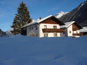 una casa cubierta de nieve frente a un árbol en Berghaus Martin en Neustift im Stubaital