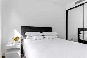 a white bedroom with a large white bed with white pillows at Scenic Wollongong Gem - City Location with Rooftop in Wollongong