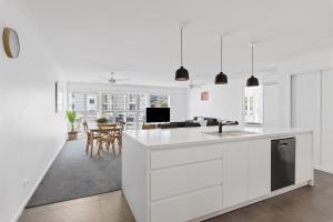 a white kitchen with a sink and a table at Seashells Sweet Retreat - Luxury apartment in Nelson Bay