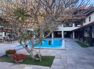 a tree in front of a building with a swimming pool at Flat 1218, no residencial monte castelo in Bezerros