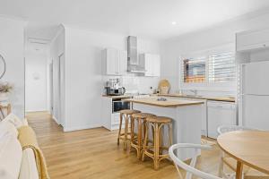 a kitchen with white cabinets and a table and chairs at Coastal Retreat Long Jetty- Toowoon Bay in Long Jetty