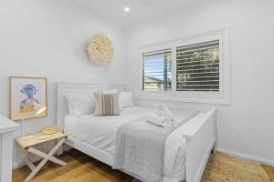 a white bedroom with a bed and a window at Coastal Retreat Long Jetty- Toowoon Bay in Long Jetty