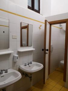 a bathroom with two sinks and a mirror and a toilet at Ostello San Marco Cortona in Cortona