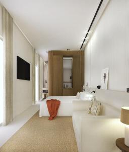 um quarto com uma grande banheira branca e uma televisão em Hotel Liautaud em Cassis