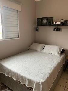 een kleine slaapkamer met een bed en een raam bij Apto ao lado da Usp e 7 minutos da Agrishow in Ribeirão Preto