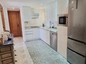 a kitchen with white cabinets and a stainless steel refrigerator at Torre Hirta 1 in Peniscola +32 photos