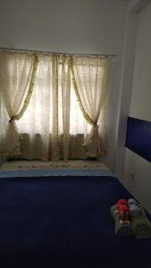 a bedroom with a window with curtains and a blue floor at Casinha Aconchegante in Guarulhos