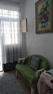 a living room with a green couch and a window at Casinha Aconchegante in Guarulhos