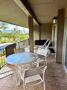 a patio with a table and chairs on a balcony at IslandVista 1BR: Ocean & Golf Bliss in Kahana