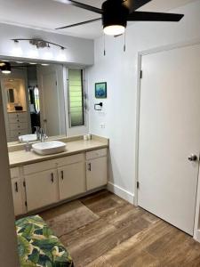uma casa de banho com um lavatório e um espelho grande em IslandVista 1BR: Ocean & Golf Bliss em Kahana
