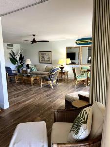 uma sala de estar com um sofá, cadeiras e uma mesa em IslandVista 1BR: Ocean & Golf Bliss em Kahana