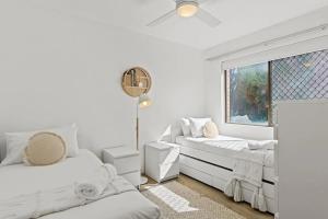 a white bedroom with two beds and a window at Beachside Serenity - 100m to Beach in Nelson Bay