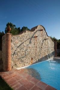 a stone retaining wall next to a swimming pool at Paraje del Hueznar in Cazalla de la Sierra