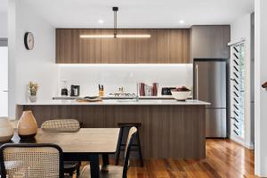 a kitchen and dining room with a table and a refrigerator at Catch the Breeze - Pet Friendly Townhouse in Newcastle