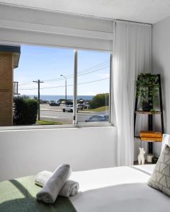 a bedroom with a bed and a large window at Seascape - 500m to Merewether Ocean baths in Merewether