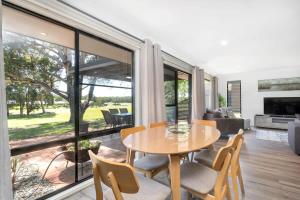 a dining room with a table and chairs in a living room at Hitters Paradise - Stay & Play in Salamander Bay in Salamander Bay