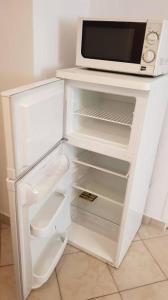 einen weißen Kühlschrank mit einer Mikrowelle darüber in der Unterkunft Fortuna Apartmanok Eger in Eger