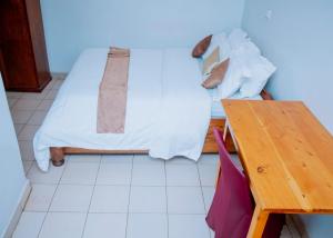 a bedroom with a bed with a wooden table at SKYLIGHT MOTEL Airport Road in Kigali
