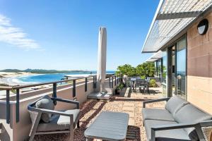 a balcony with chairs and tables and the ocean at Sea View Retreat in Nelson Bay