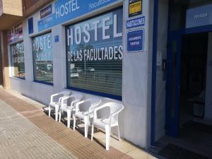 a row of white chairs sitting outside of a hospital at Hostel de las Facultades in Santander