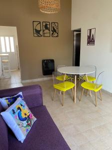 sala de estar con sofá púrpura, mesa y sillas en Las Balda, tu casita en Viedma, en Viedma