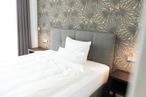 a bedroom with a white bed with a wall at Toploft The Aparthotel in Crailsheim