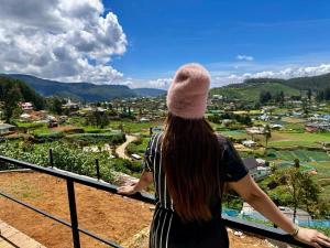 una mujer parada en un balcón con vistas a un valle en Viewscape en Nuwara Eliya